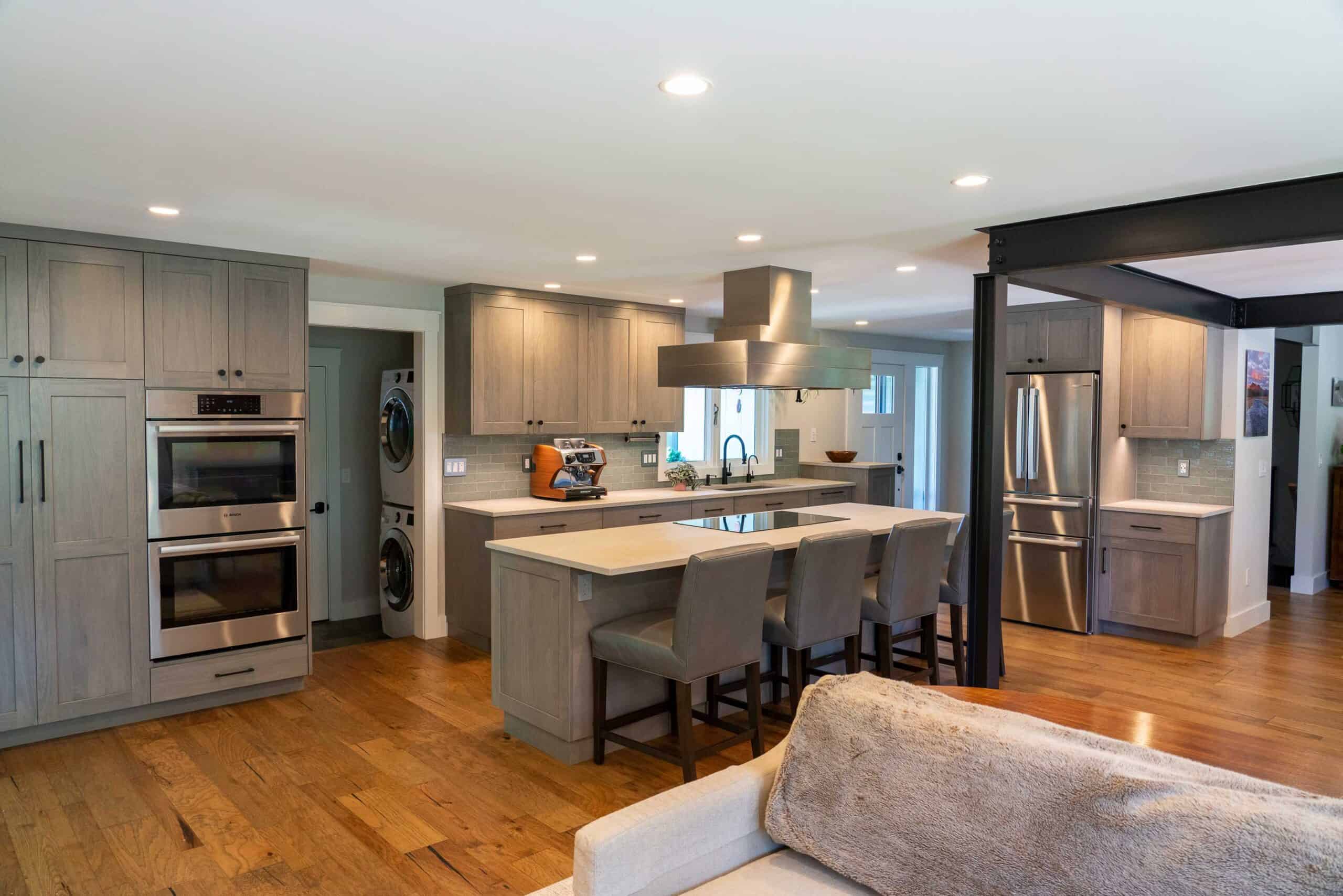 Spacious modern kitchen with gray cabinetry, stainless steel appliances, and a large island for cook.