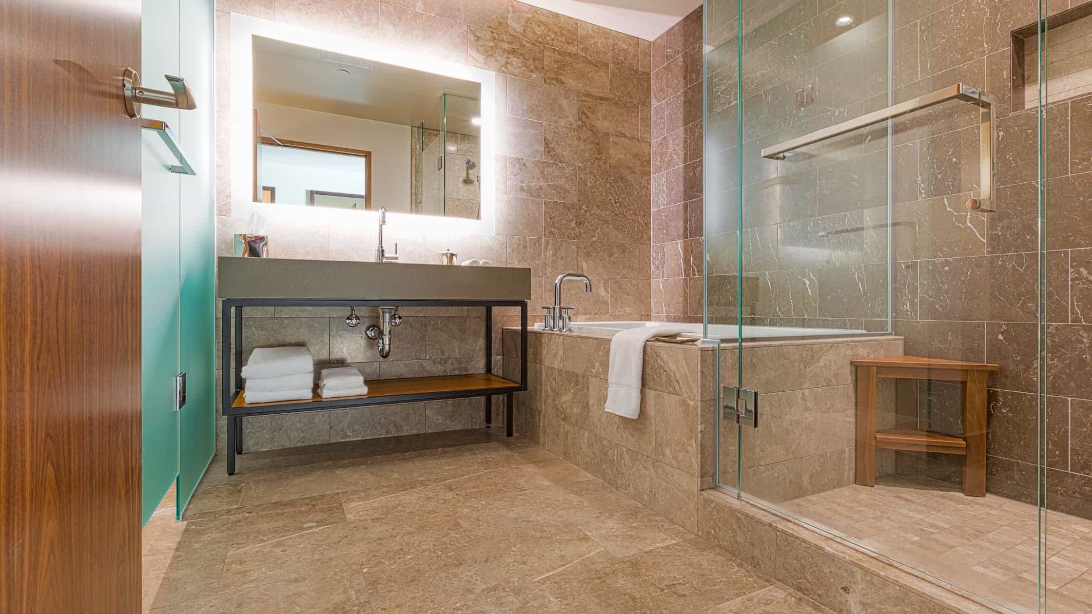 Modern bathroom with walk-in shower and bathtub, featuring elegant tile work and contemporary fixtur.