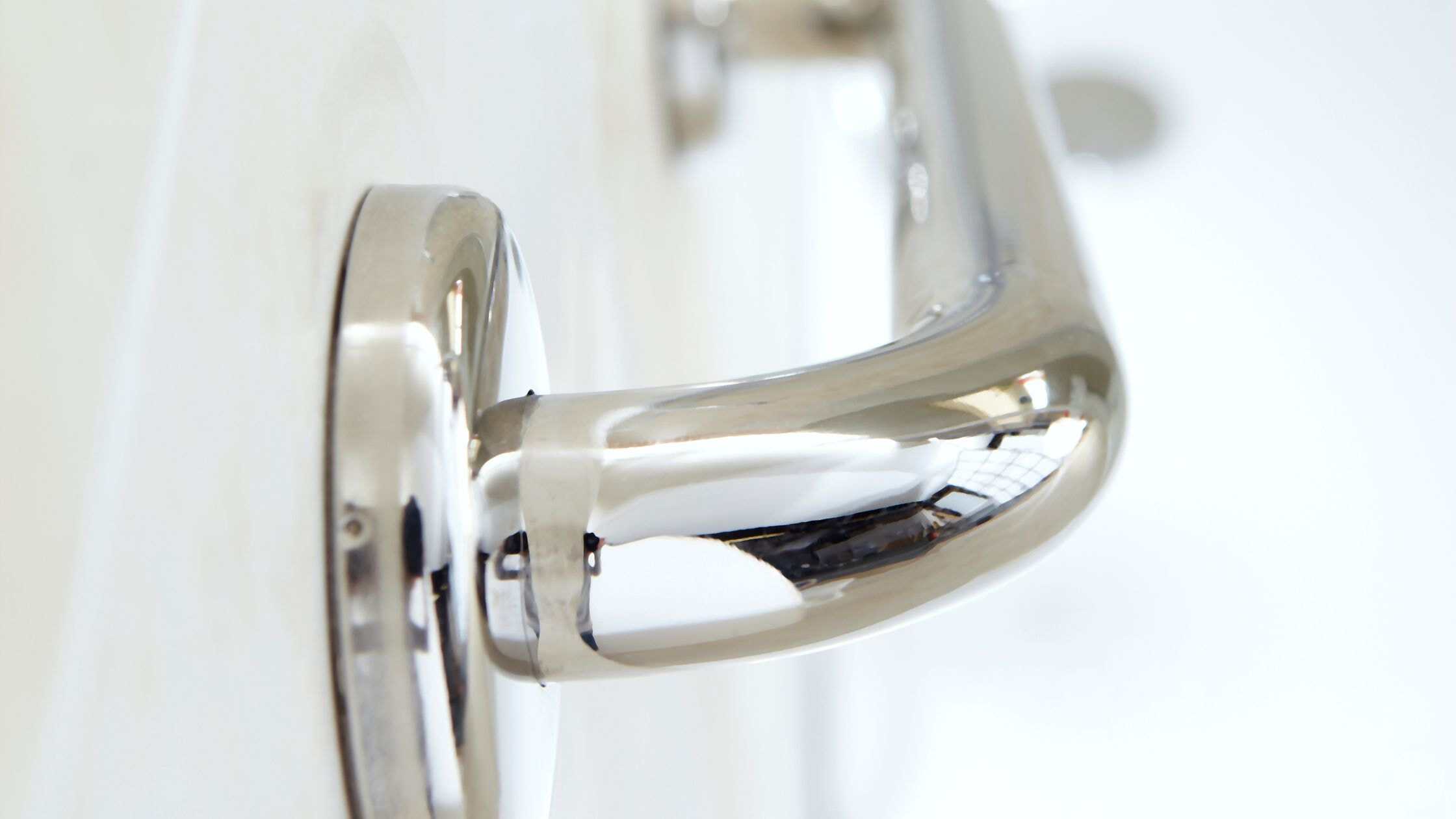 Up of a sleek, chrome door handle in a residential setting.