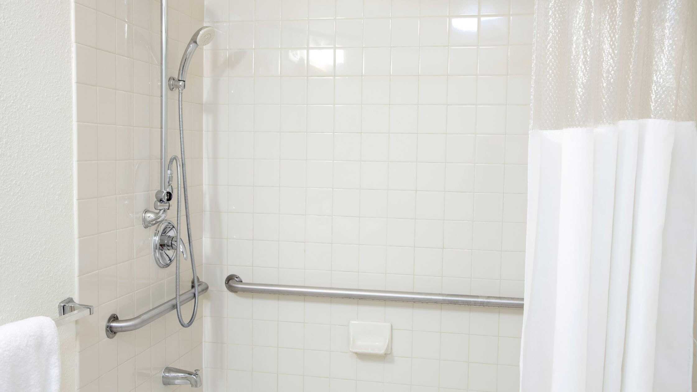 Accessible shower with grab bars and handheld showerhead.