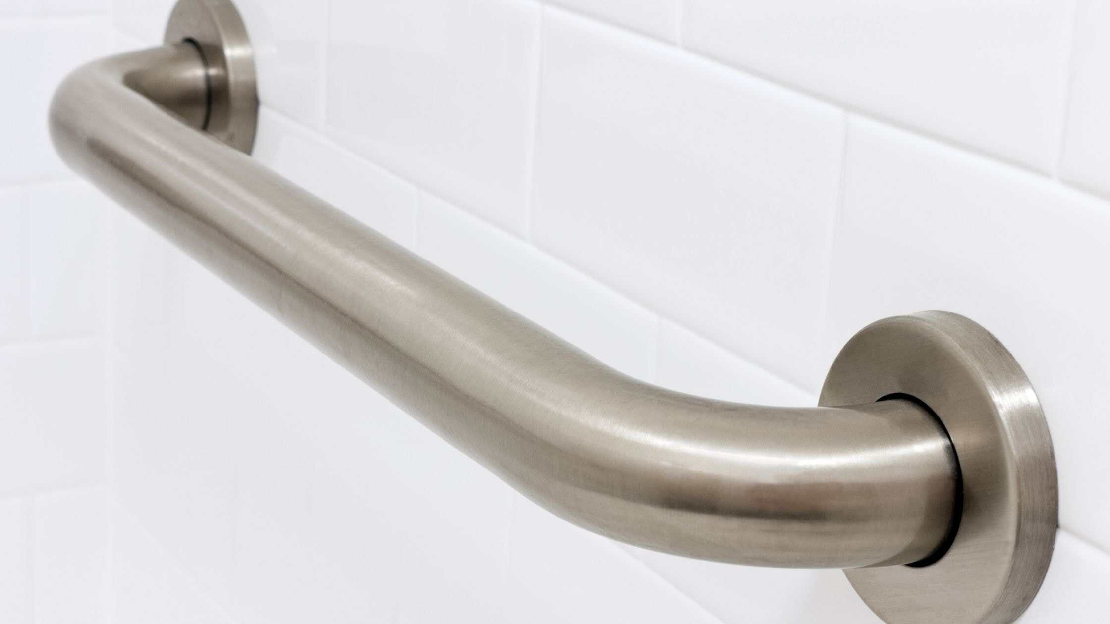 Handrail installed on a white tiled wall for safety and support.