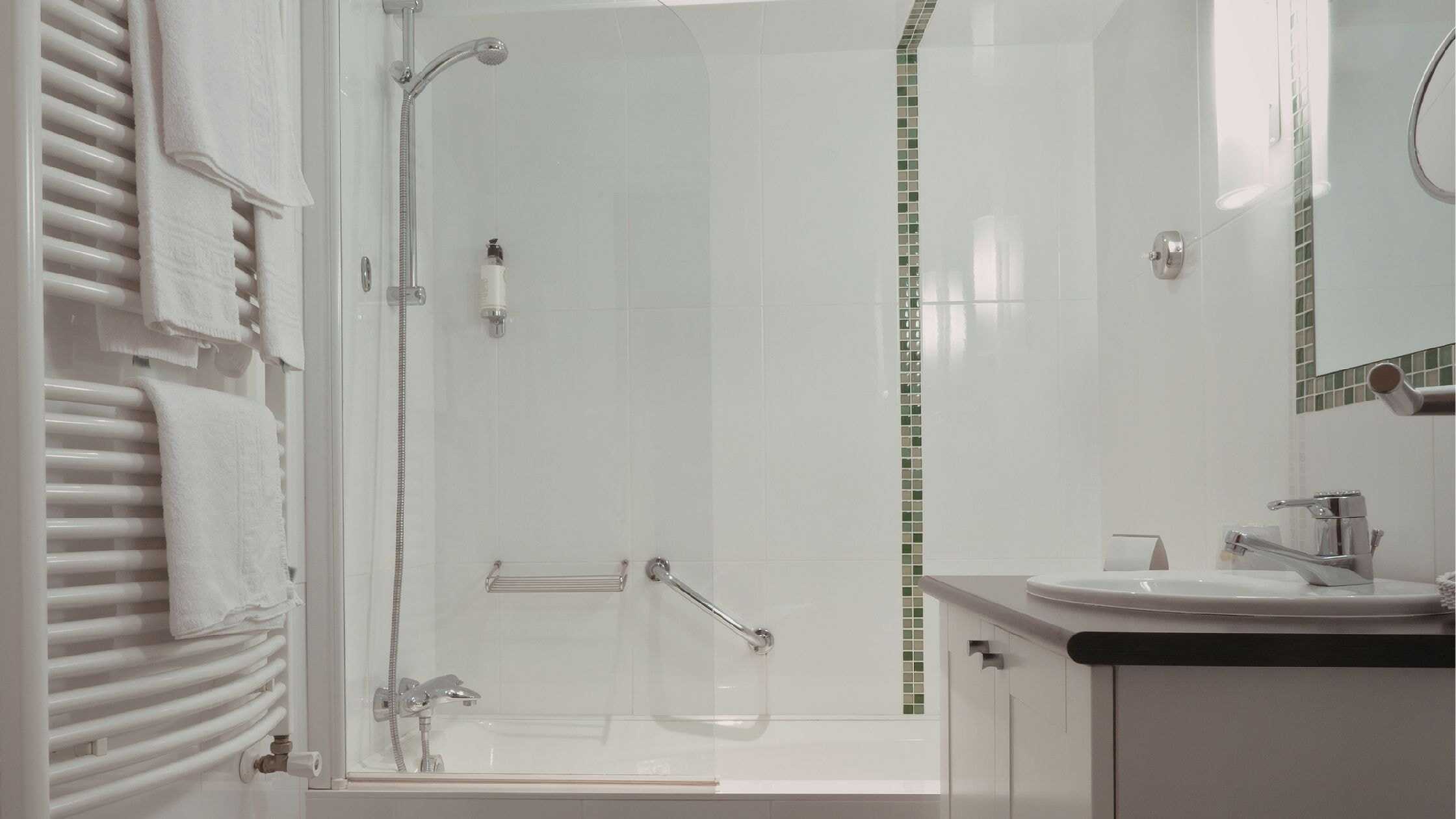 Bright modern bathroom with walk-in shower, white tiles, and accessible features.