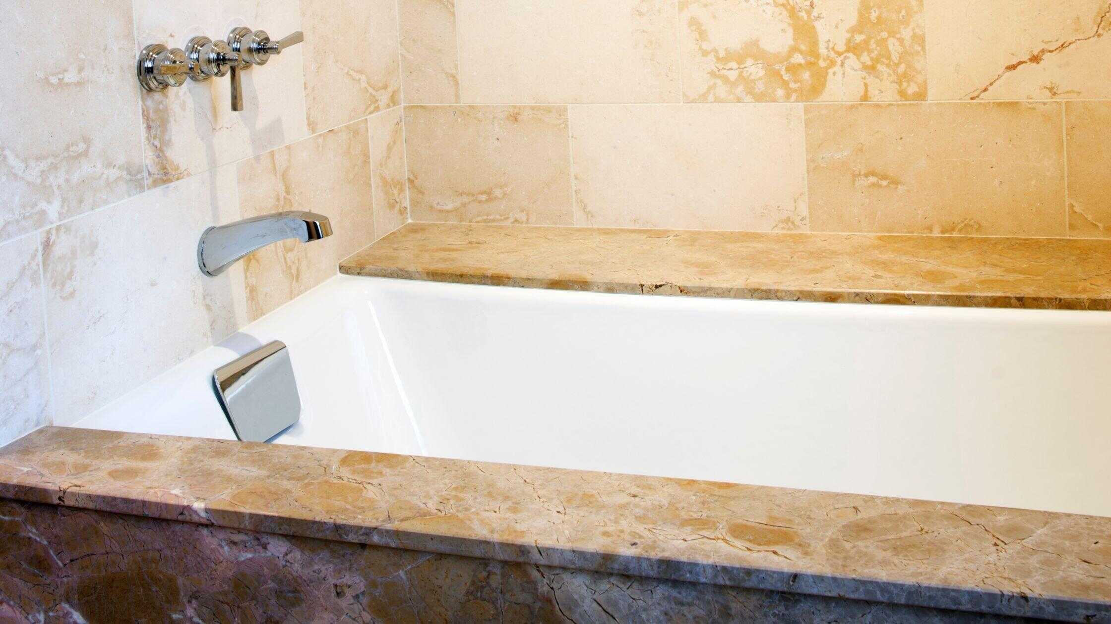 Elegant bathtub with marble surround in a luxurious bathroom setting.