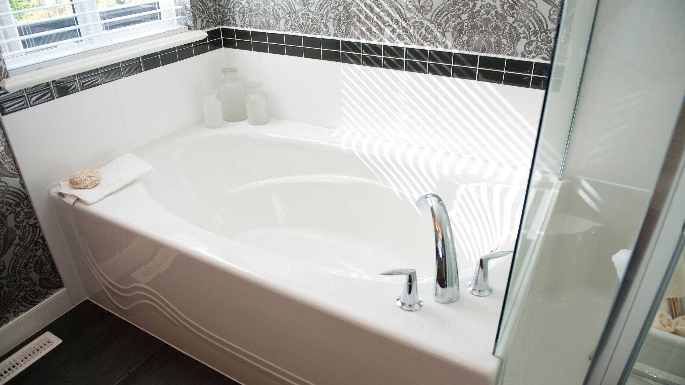 Elegant white bathtub in a contemporary bathroom with decorative tiles and natural light.