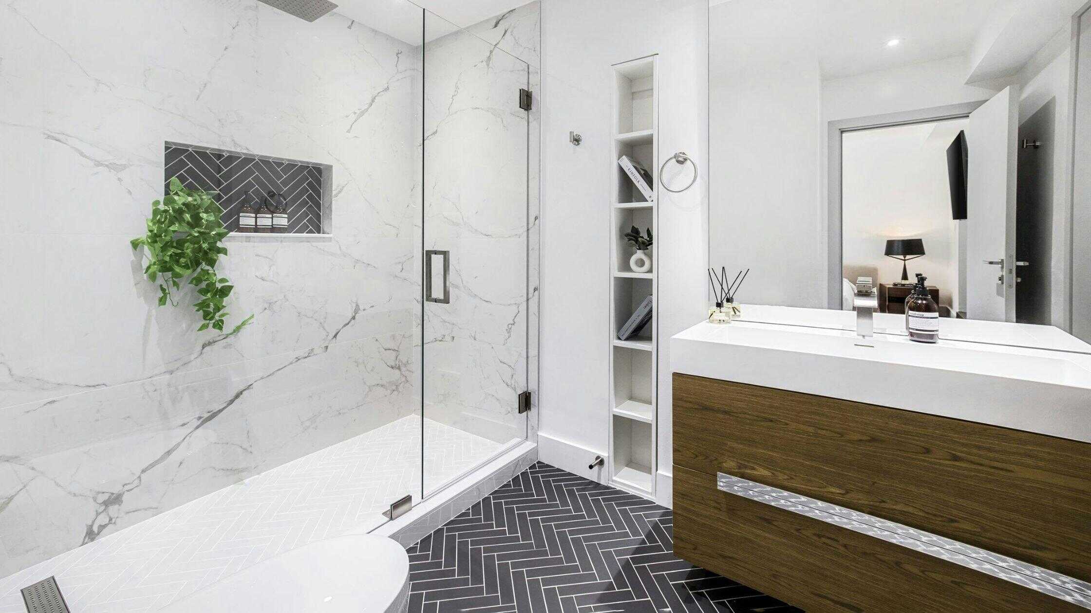 Elegant bathroom with marble walls and a glass shower enclosure by Two Aspens Builders.