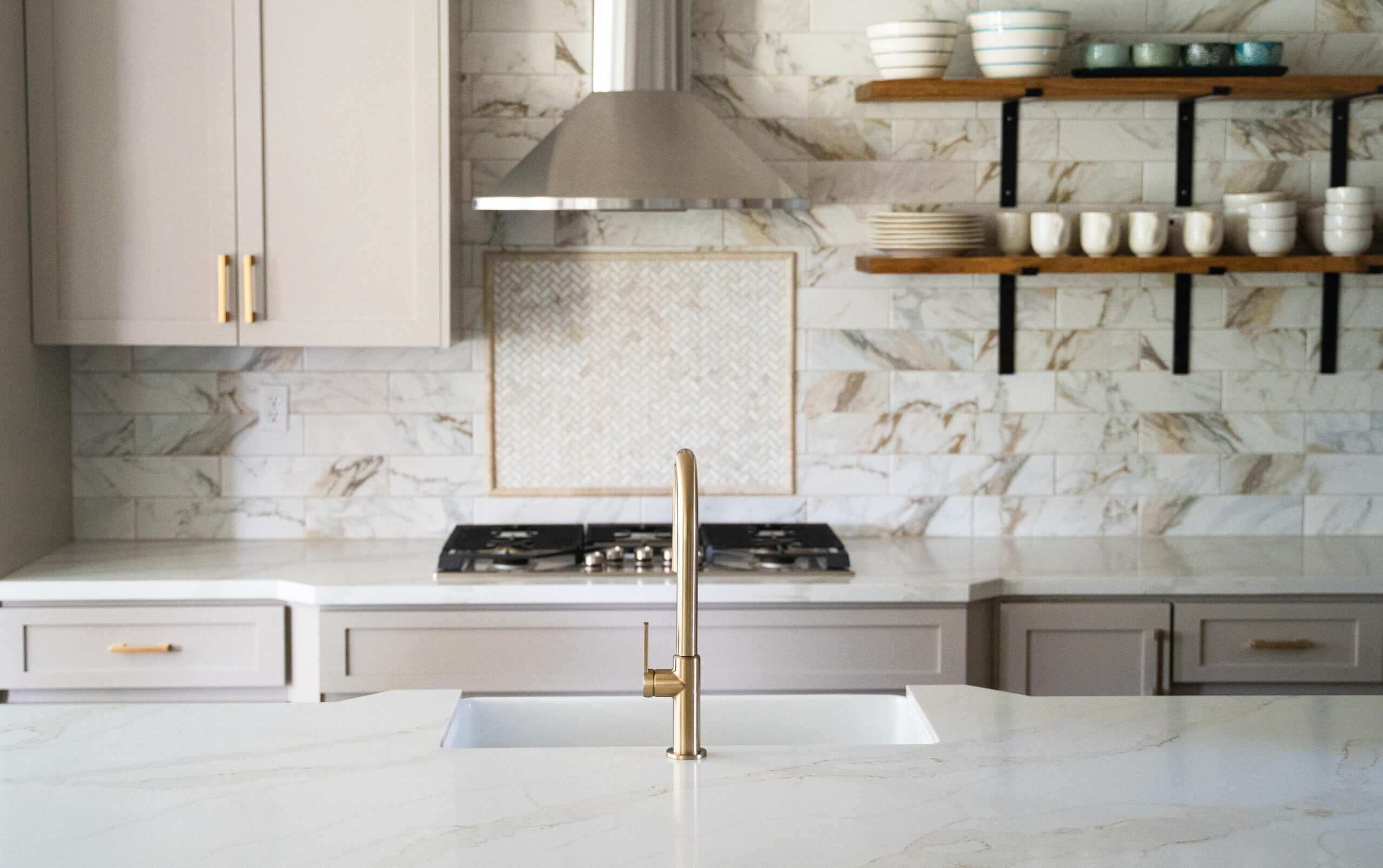 Modern kitchen with white marble countertops and open shelving.